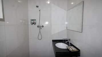 Un baño con ducha, lavamanos y espejo.