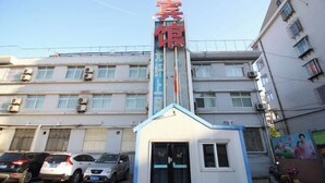 A building with a prominent sign, a small entrance, and parked cars. - Industry Hotel (Zhaoyuan)