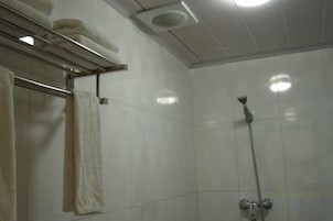 Un baño con ducha, toallero y rejilla de ventilación en el techo.