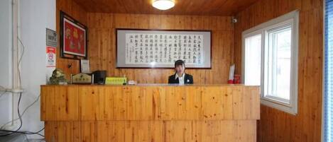 A reception desk with a framed sign, a clock, and a small statue.