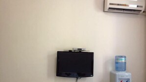 A wall-mounted television, a water dispenser, and an air conditioner. - Industry Hotel (Zhaoyuan)