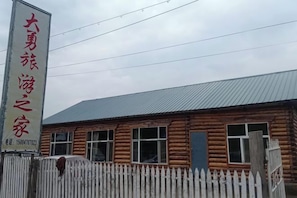 A wooden building with a signboard, a white picket fence, and a metal roof.