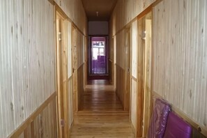 Un couloir étroit aux murs et au plancher en bois, qui mène à une porte au fond.