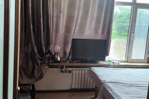 A room with a bed, a window with curtains, a radiator, and a television on a stand. - Dayong Travel Home (Erguna Shiweizhen Linjiang Branch) (Ergun)