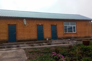 A wooden log cabin with a metal roof, two front doors, and a small window.