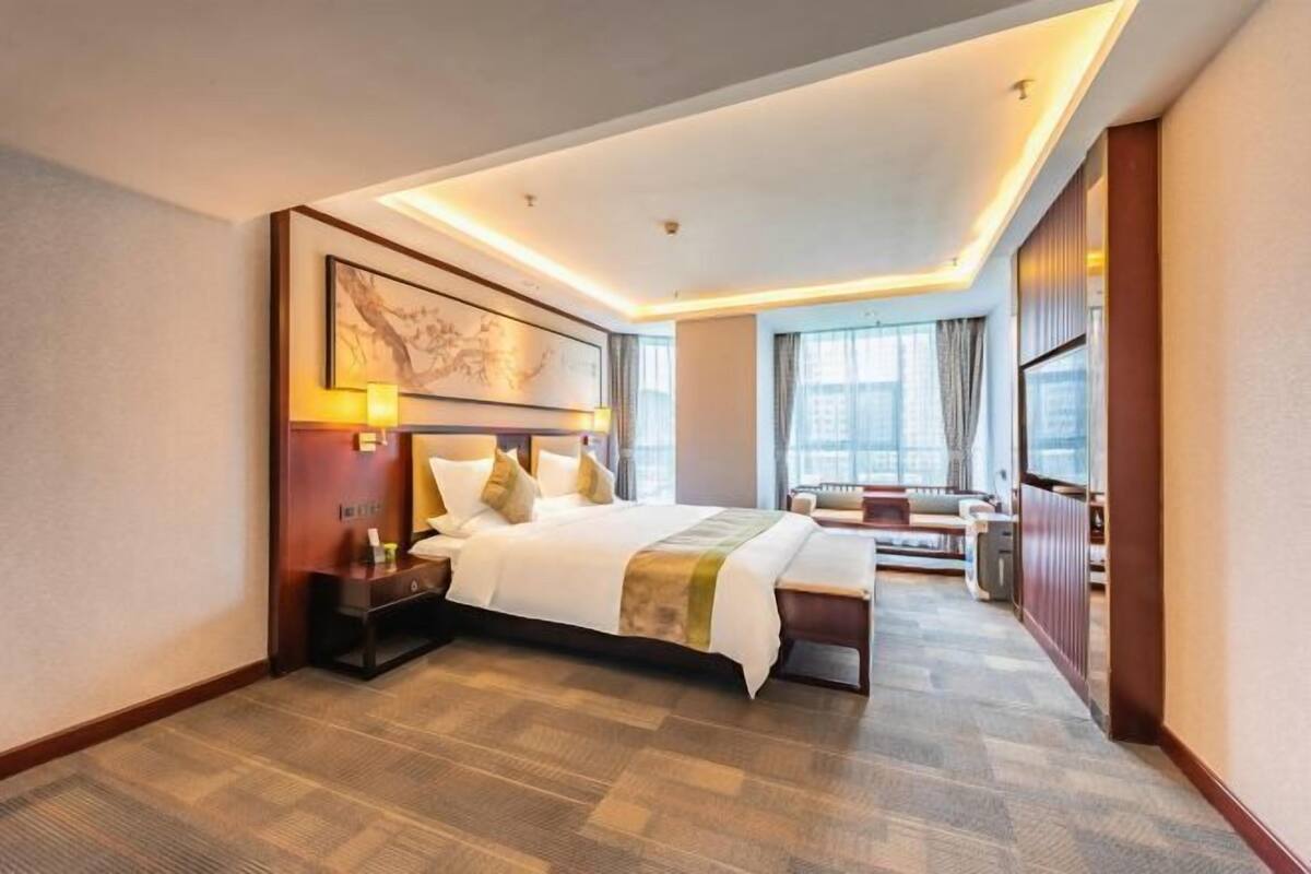 Ein Hotelzimmer mit einem großen Bett, Nachttischen, einem Schreibtisch und einem Sessel.