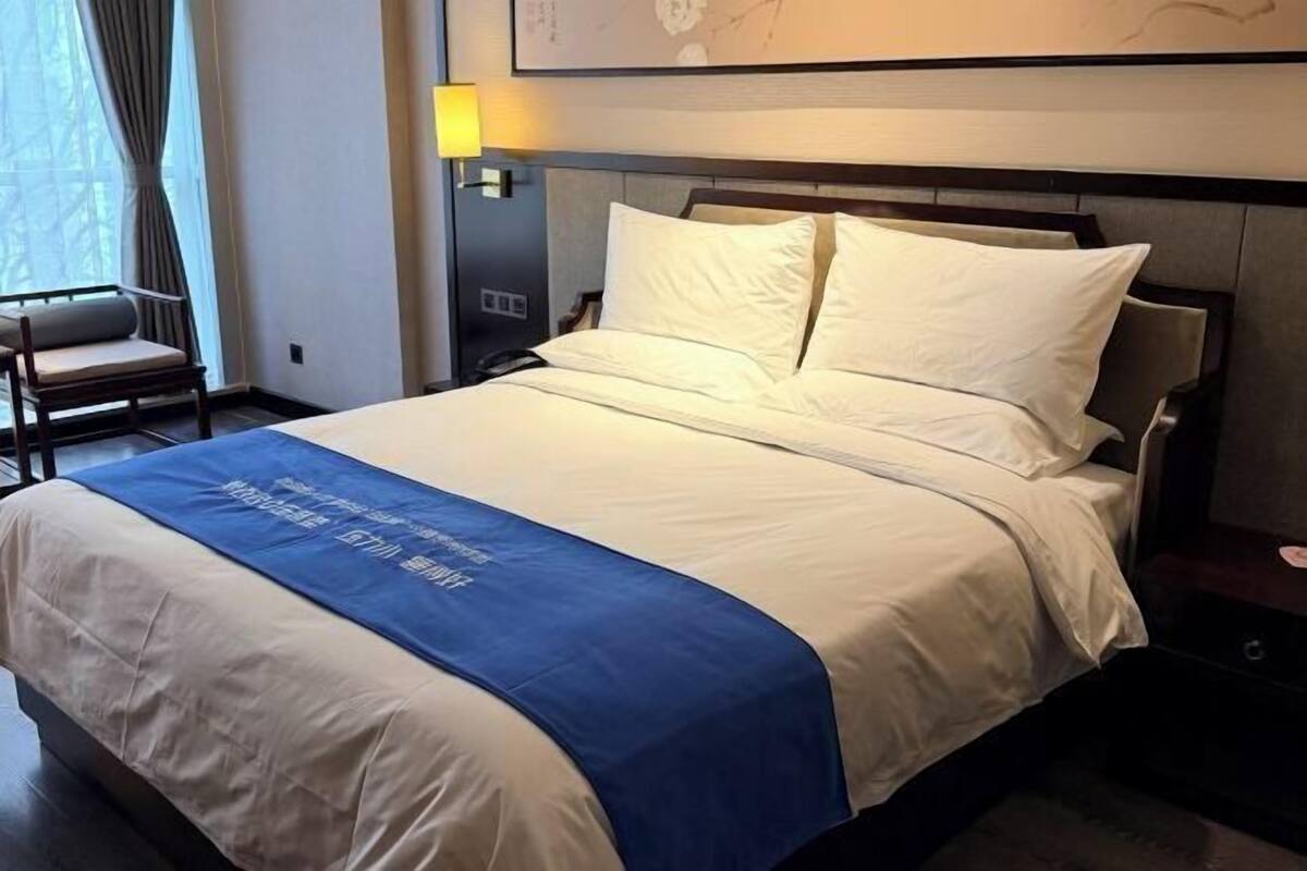 Ein Hotelzimmer mit Bett, Sessel, Nachttisch und Lampe.