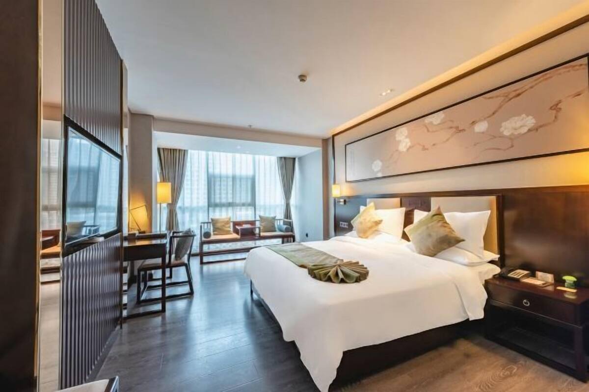 Ein Hotelzimmer mit einem großen Bett, Nachttischen, einem Schreibtisch und einem Stuhl.