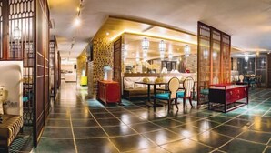 A spacious hotel lobby with a dining area, a reception desk, and a decorative partition. - Huawen International Hotel (Shijiazhuang)