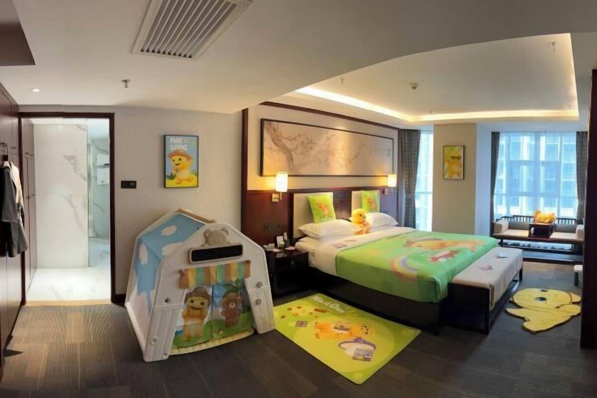 Ein Hotelzimmer mit Bett, Nachttisch, Lampe und einem Spielzelt.
