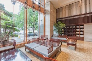 Eine Lobby mit Sitzgelegenheiten, einem Bücherregal und großen Fenstern.