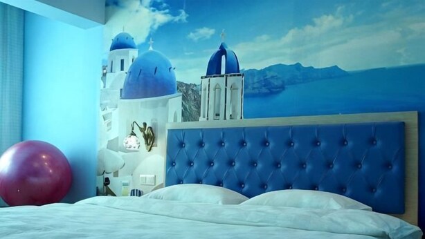 A bedroom with a bed, a blue headboard, a red exercise ball, and a mural of a blue-domed building. - Lianyungang Green Apple Hotel Apartment (Lianyungang)