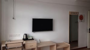 A room with a bed, a desk, a chair, a television, and a window. - Lianyungang Green Apple Hotel Apartment (Lianyungang)