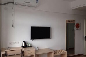 Ein Zimmer mit einem Bett, einem Schreibtisch, einem Stuhl, einem Fernseher und einem Fenster.