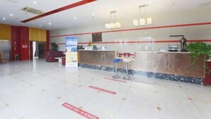 A hotel reception area with a modern design, featuring a reception desk, seating area, and a large plant. - Yu'an Hotel (Lu'an Guangcai Great Market Railway Station) (Lu'an)