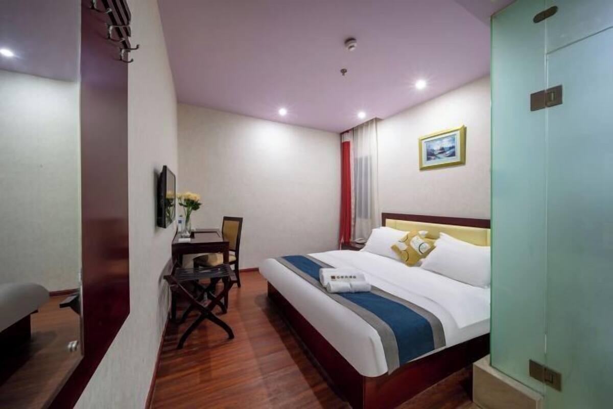 A hotel room with a bed, a desk, and a chair.