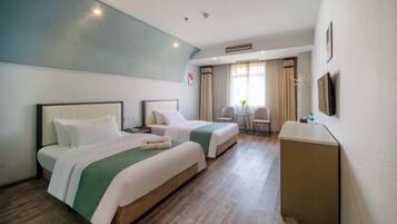 Ein Hotelzimmer mit zwei Betten, einem Schreibtisch und einem Sessel.