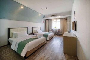 A hotel room with two beds, a desk, and a chair.