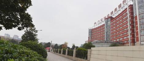 A paved walkway with a low wall on one side and a building with red and white signage in the background.