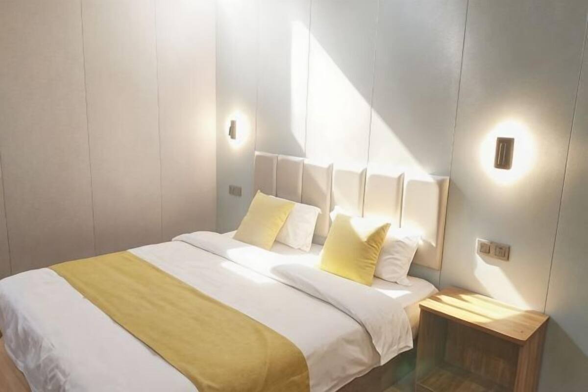 Une chambre à coucher avec un lit, des tables de chevet et des lampes fixées au mur.