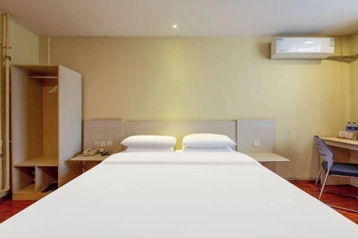 Une chambre d’hôtel équipée d’un lit, d’un bureau, d’une chaise, d’une armoire et d’un appareil de climatisation.
