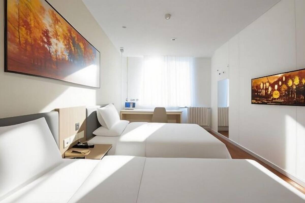 Une chambre d’hôtel avec deux lits, un bureau et une grande fenêtre.