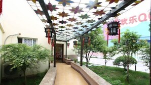 A covered walkway with a tiled floor, surrounded by greenery and decorative hanging elements. - Homeinn Hotel (Nanjing South Railway Station Shengtai West Road Cuipingshan Subway Station) (Nanjing)