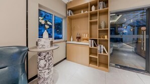 A modern interior with a marble table, a blue chair, and a wooden bookshelf with books and decorative items. - Homeinn Hotel (Nanjing South Railway Station Shengtai West Road Cuipingshan Subway Station) (Nanjing)