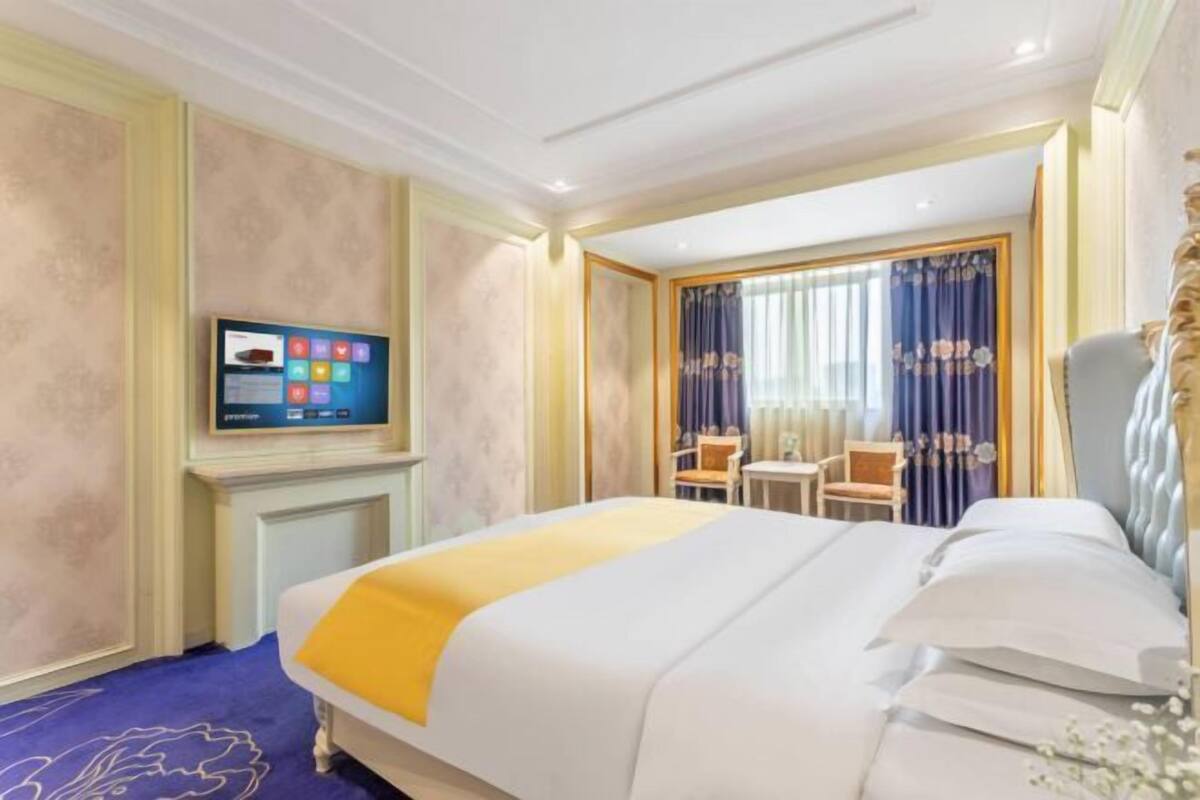 Ein Hotelzimmer mit Bett, Fernseher, kleinem Tisch und Stuhl.
