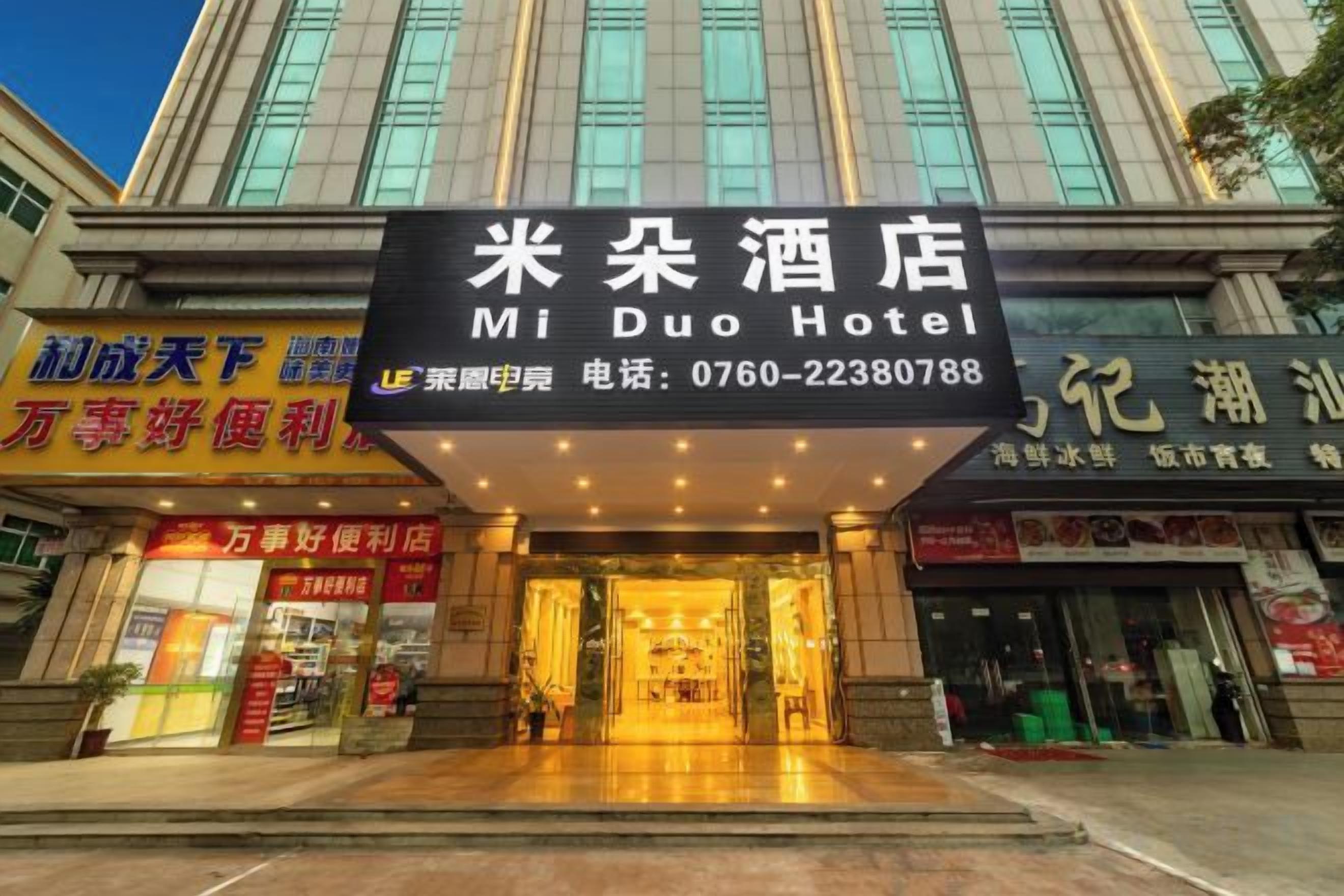 The entrance to Mi Duo Hotel with a prominent sign, a covered entrance, and a visible storefront with signage in a foreign language.