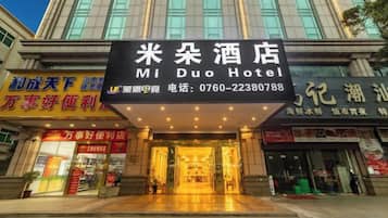 The entrance to Mi Duo Hotel with a prominent sign, a covered entrance, and a visible storefront with signage in a foreign language.