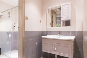 Un baño con ducha, lavamanos y espejo.