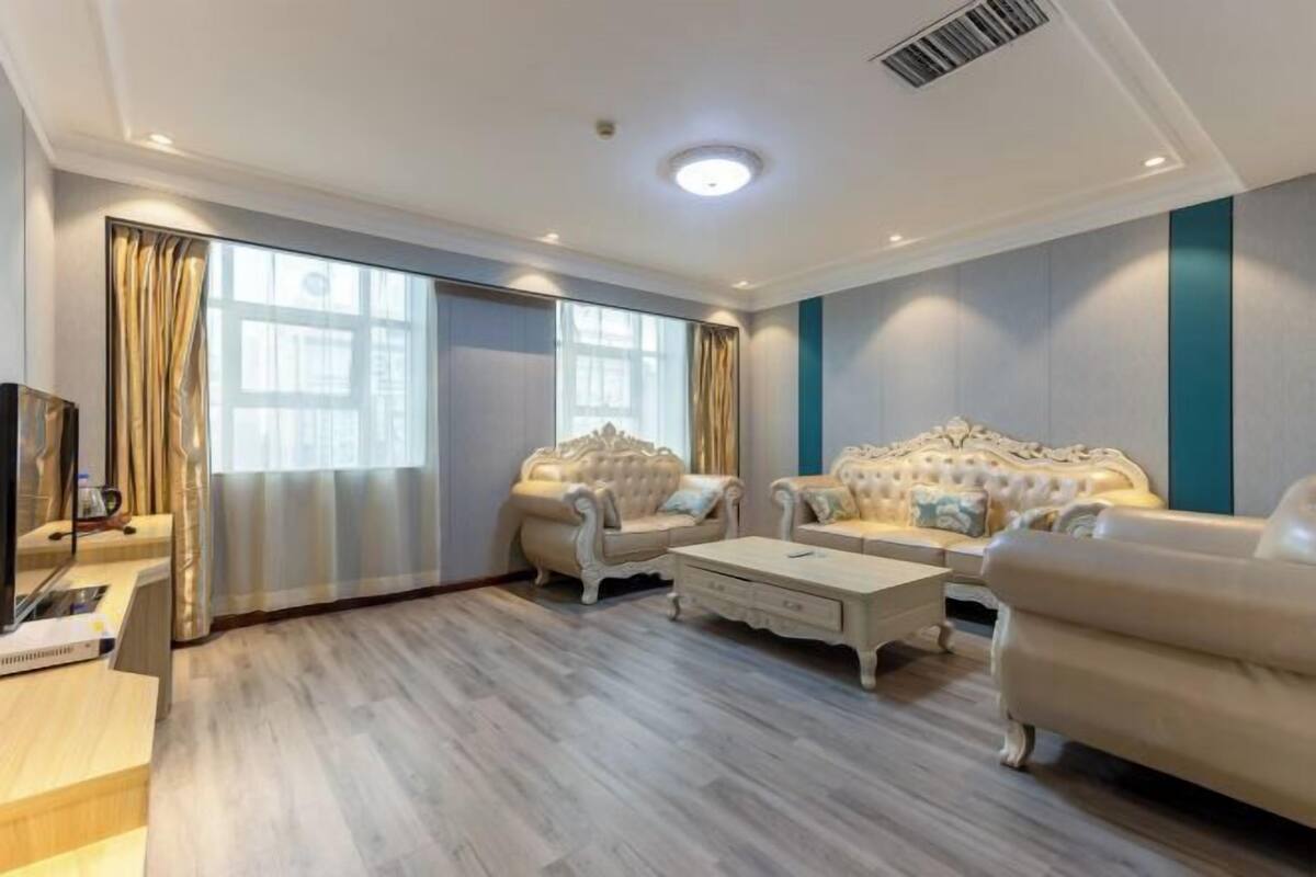 Ein geräumiges Wohnzimmer mit großem Fenster, zwei bequemen Sofas, einem Couchtisch und einem Fernseher.