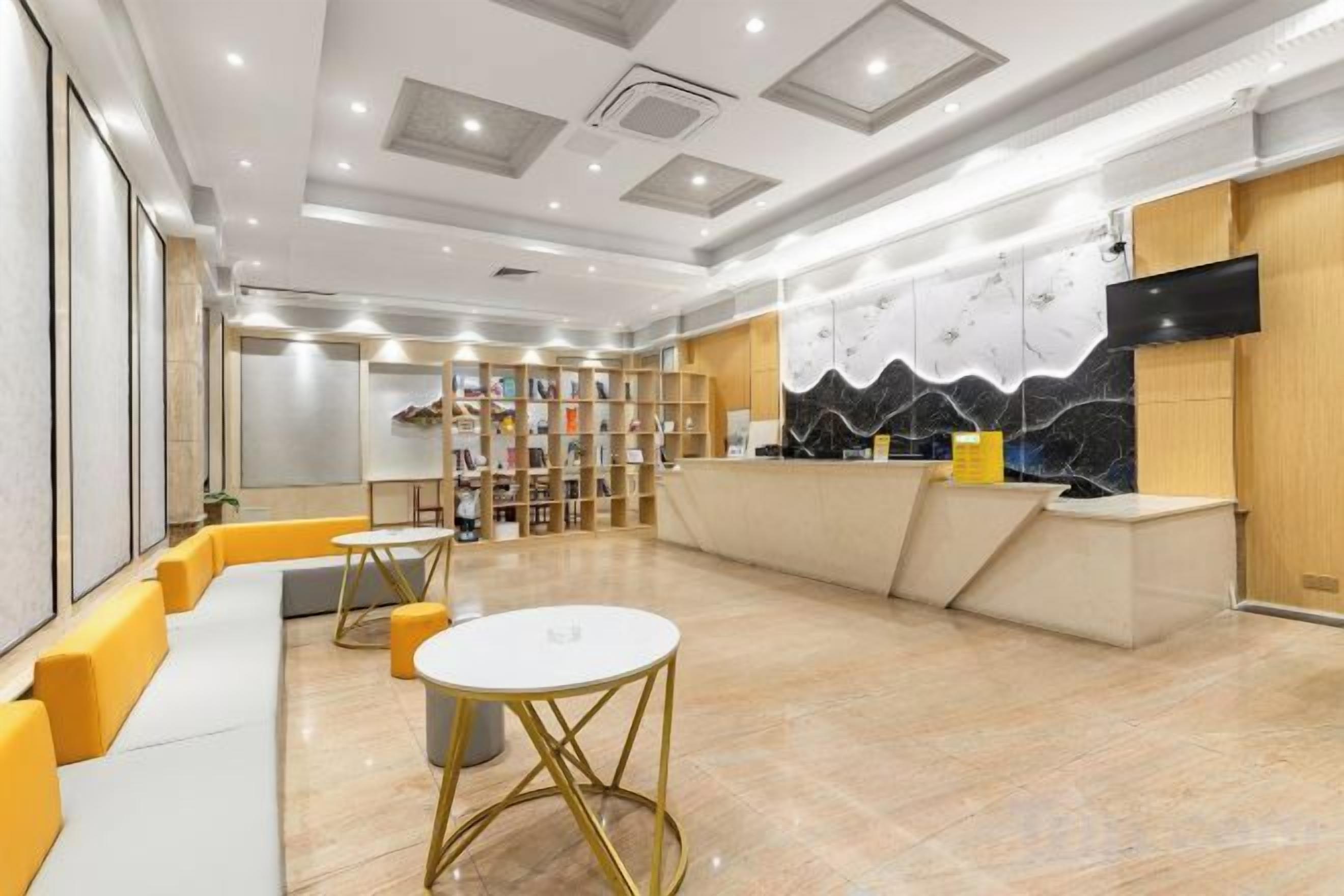 Un hall de hotel con mostrador de recepción, zona de estar y una estantería.