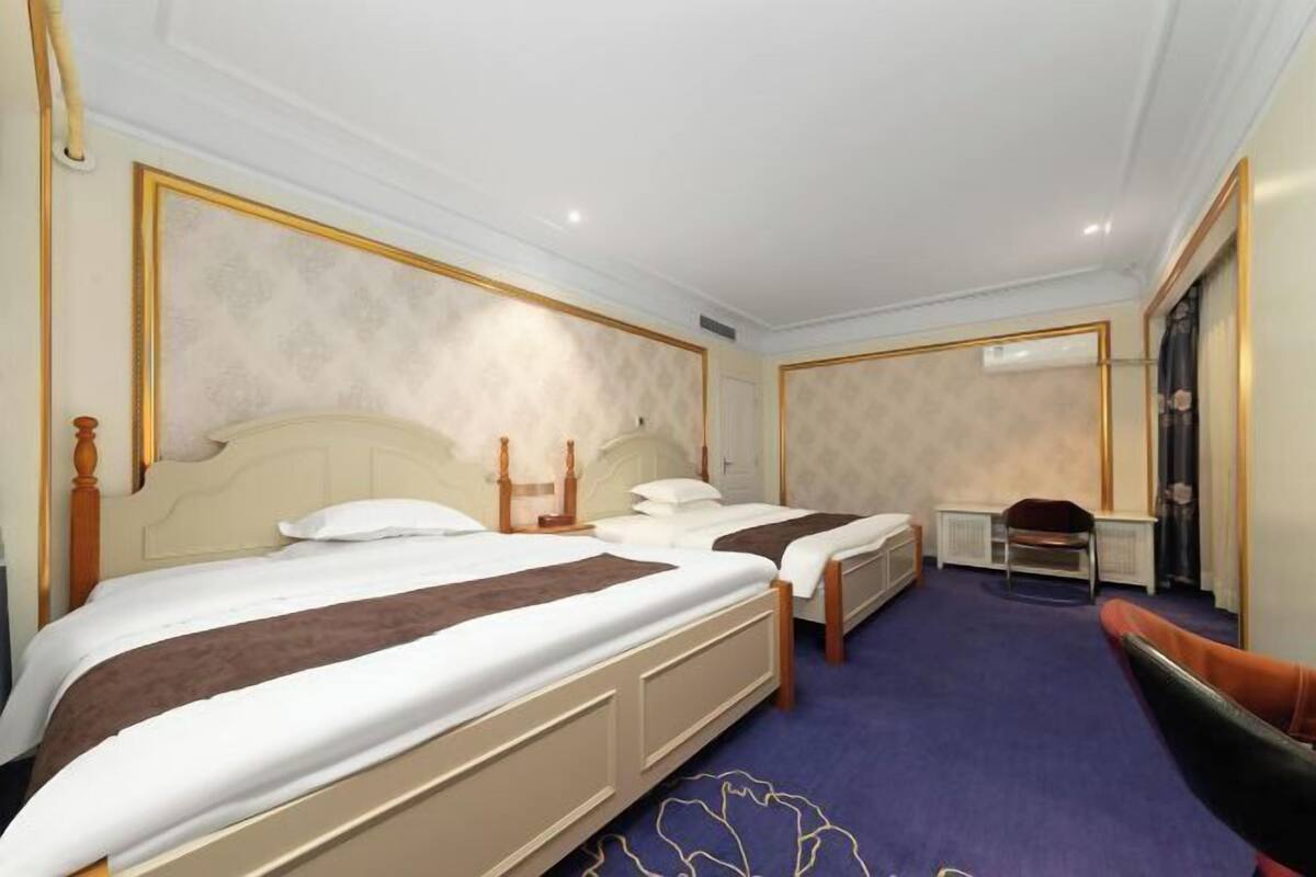 Ein Hotelzimmer mit zwei Betten, einem Sessel, einem Schreibtisch und einer Heizung.
