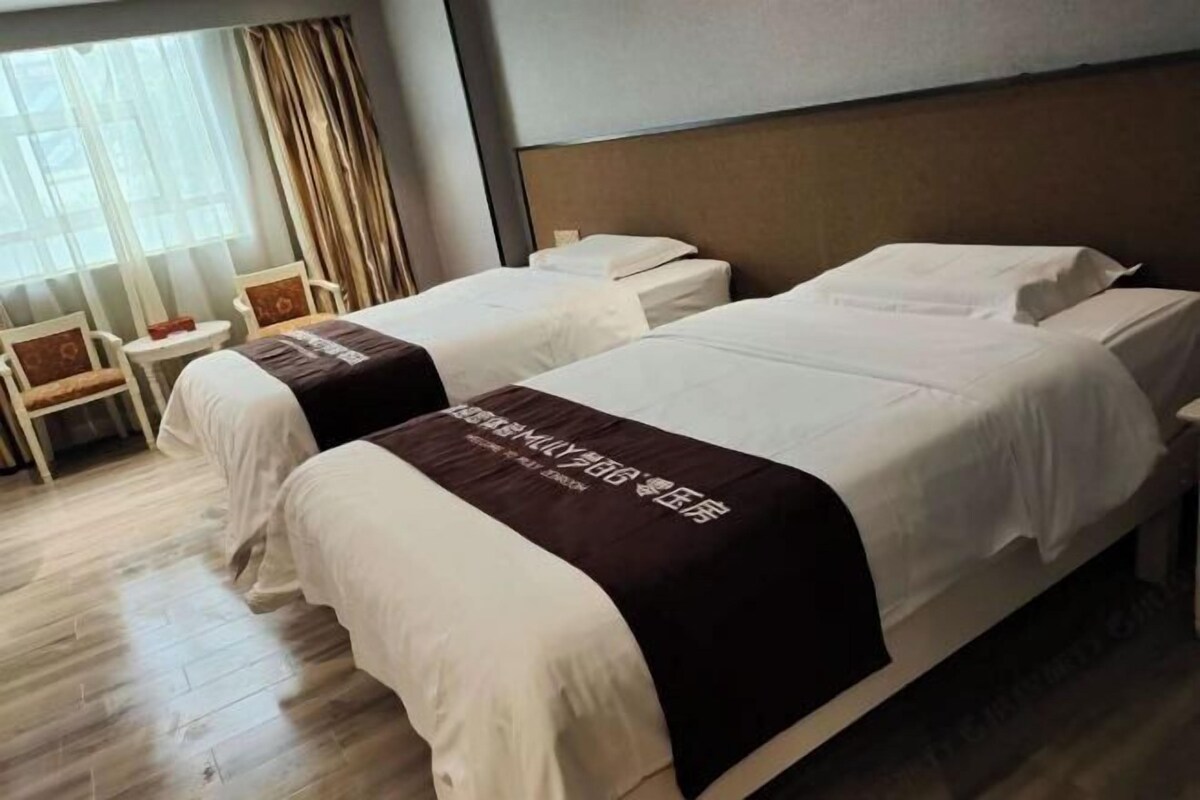 Una habitación de hotel con dos camas, una mesita y una silla.