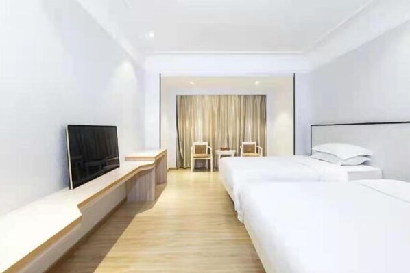Habitación de hotel con televisión, escritorio, dos camas y una silla.