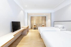 Habitación de hotel con televisión, dos camas, escritorio y una silla.