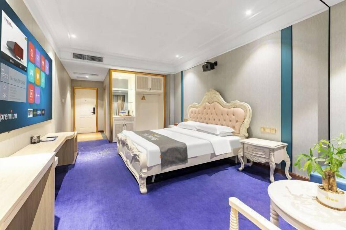 Ein modernes Hotelzimmer mit einem großen Bett, einem Schreibtisch, einem Frisiertisch und einem durch eine offene Tür einsehbaren Badezimmer.