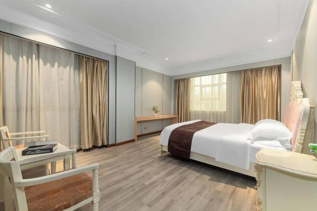 Ein Hotelzimmer mit Bett, Schreibtisch, Stuhl und einem großen Fenster.