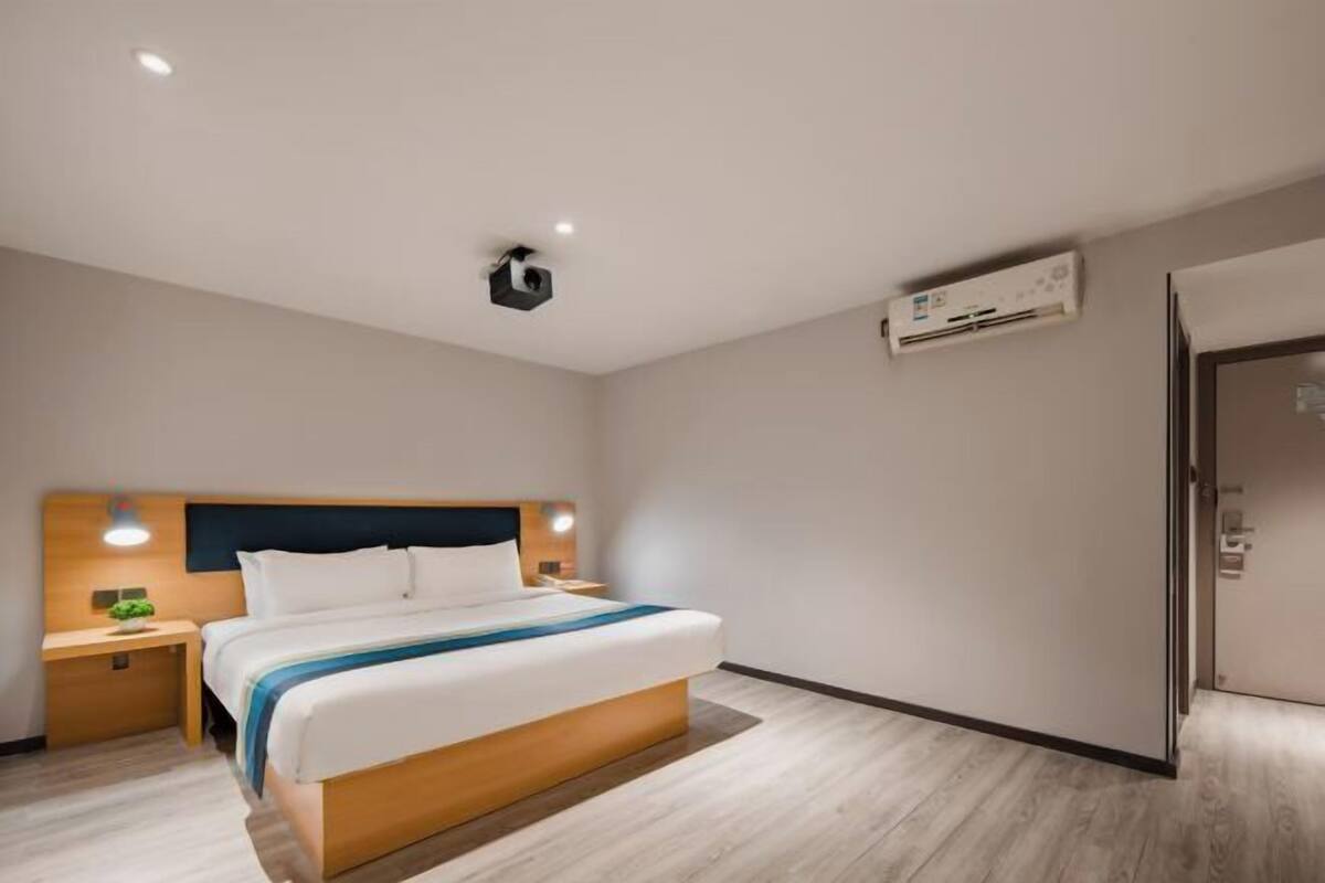 Ein Hotelzimmer mit Bett, Nachttischen, einer Klimaanlage und einer Tür.