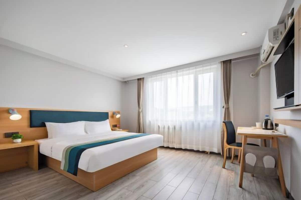 Ein Hotelzimmer mit Bett, Nachttisch, Stuhl, Schreibtisch und Fernseher.