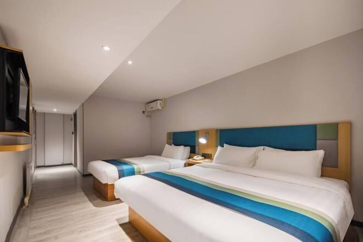 Ein Hotelzimmer mit zwei Betten, einem Fernseher, einem Schreibtisch und einem begehbaren Kleiderschrank.