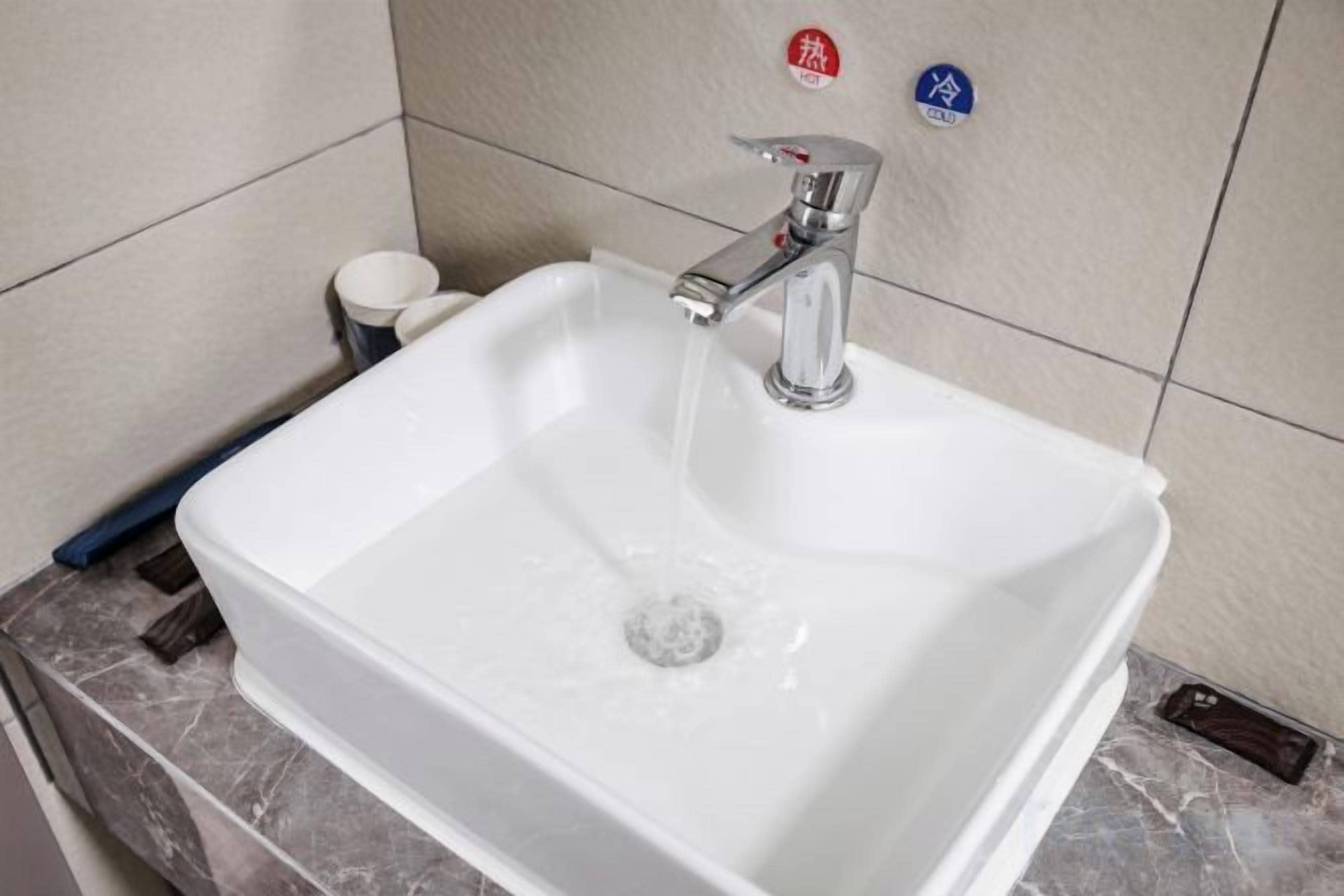 A bathroom sink with running water, a soap dispenser, and a hand dryer.