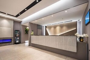Una moderna área de recepción con un mostrador elegante, un acuario integrado y un espejo grande.