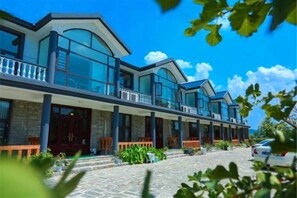 Ein modernes Hotel mit überdachtem Außenbereich, mehreren Balkonen und einer Steinfassade.