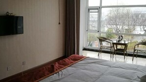 Habitación de hotel con cama, televisor en la pared y un amplio ventanal con vistas al exterior.