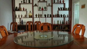 Una mesa redonda de vidrio con sillas de madera en una habitación con estantes llenos de objetos decorativos.