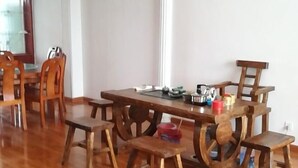 Un comedor con una mesa y sillas de madera, una ventana y una cocina visible al fondo.