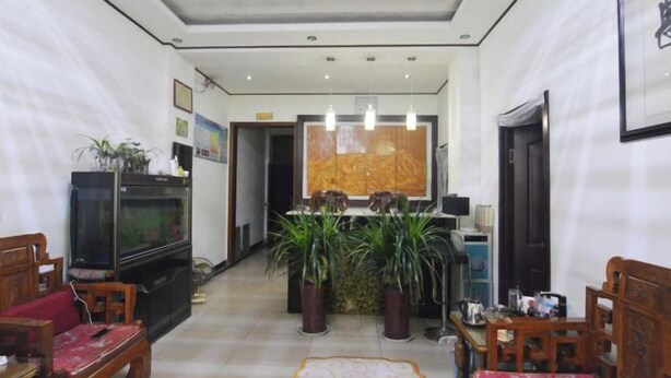 A hotel lobby with a reception desk, potted plants, a television, and wooden furniture. - Gaochun Tianhao Hotel (Gaoyi)